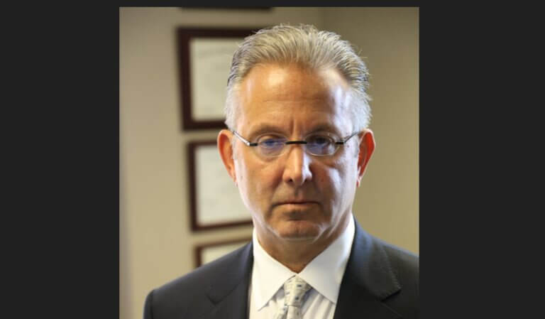 Dog Bite Attorney Jeffrey Penneys Wearing Charcoal Suit and White Shirt with Gold Tie.